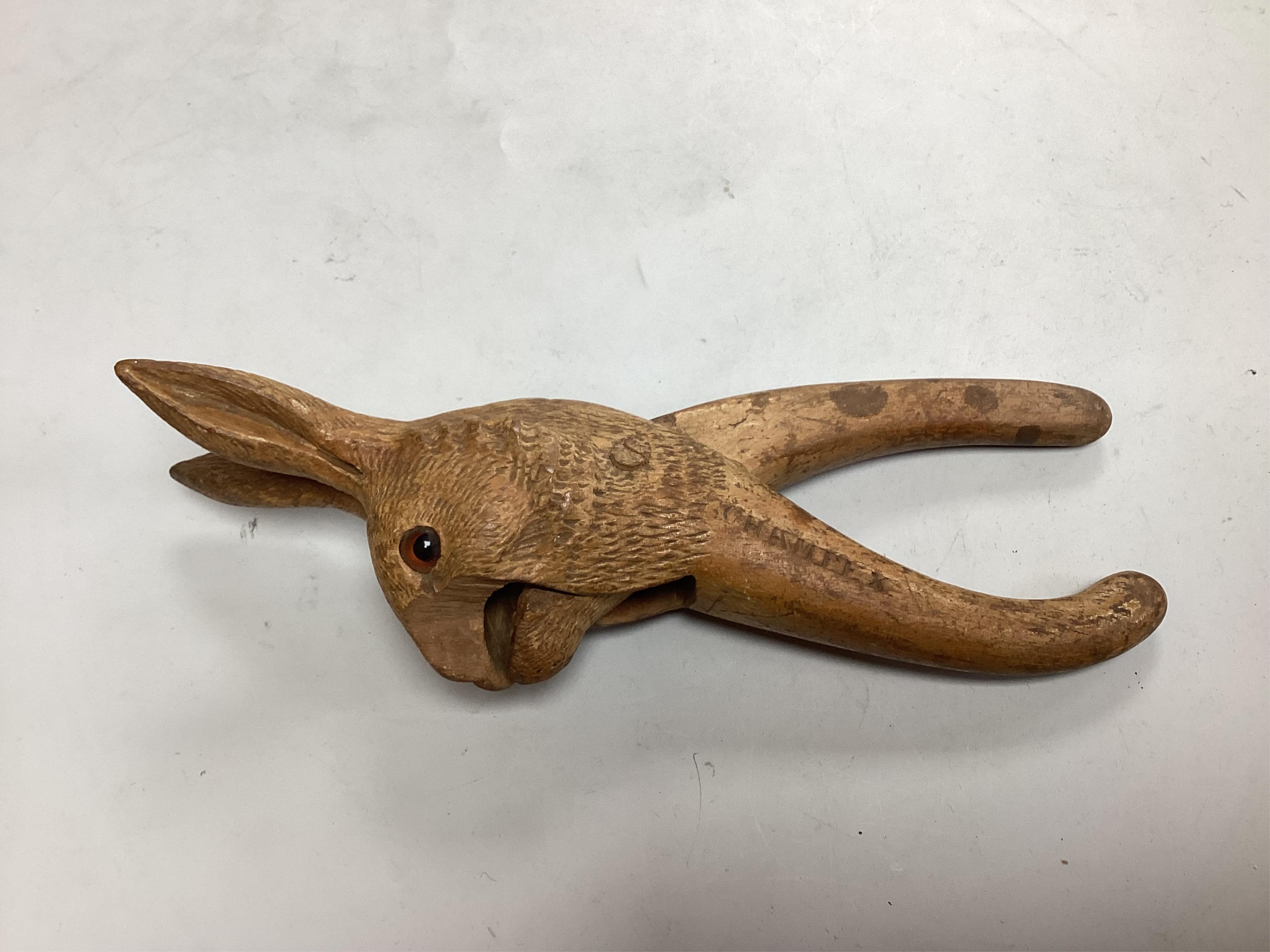 A pair of late 19th century Black Forest nutcrackers carvdd as a hare with glass eyes (loss) signed Champlex and a screw action novelty nutcracker carved with the head of a smiling man- 16.5cm high